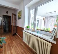 A hallway in a family house with a wooden decor floor and flowers on the windowsill.