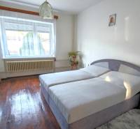 A bedroom in a family house with a wooden decor floor, a bed, and a wardrobe.