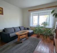 Living room in a family house with a corner sofa, carpet, and wooden decor flooring.