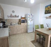 A family house kitchen with wooden decor, a dining table, and green chairs.