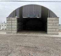 Warehouses and halls in Ladce with arched roofs and concrete entrances.