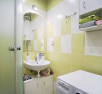 Bathroom in a 2-room apartment with a sink, washing machine, and green tiles.