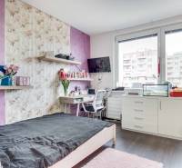 A room in a 2-room apartment with a bed, a desk, and a floor with a wooden decor.