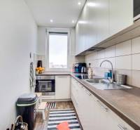 A kitchen in a 2-room apartment with a wooden decor floor and stylish cabinets.