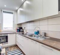A kitchen in a 2-room apartment with a window, built-in oven, and floor with wood decor.