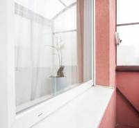 Balcony of a 2-room apartment with a flowerpot and curtains, exterior of Nové Zámky.