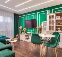 Living room in a two-room apartment with a wooden decor floor and green furniture.
