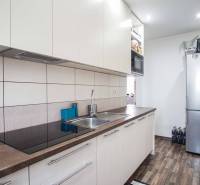 A kitchen in a 2-room apartment with furnishings and a wooden decor floor.