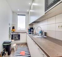 A kitchen in a 2-room apartment with a wooden floor decor and white cabinets.