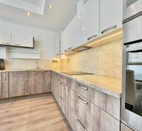 A kitchen in a 3-room apartment with a wood-patterned floor and modern cabinets.