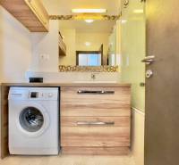 Bathroom with a washing machine and a sink in a 3-room apartment, floor with wood decor.