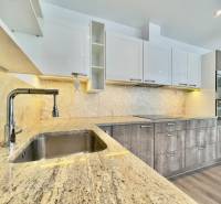 A kitchen in a 3-room apartment with a wooden decor floor and a granite countertop.