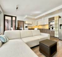 Living room of a three-room apartment with a white sofa and a kitchen unit.