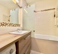 A bathroom with a bathtub, sink, mirror, and decorative tiles in a 3-room apartment.
