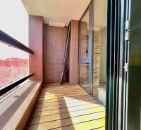 Balcony of a 3-room apartment with a wooden decor floor and a glass partition.