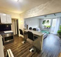 A kitchen connected to the living room with a wooden decor floor in a 3-room apartment.