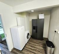 A kitchen in a 3-room apartment with a washing machine and a refrigerator. Floor with wooden decor.