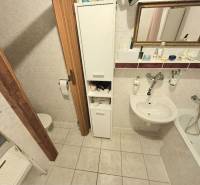 A bathroom in a 3-room apartment with a bathtub, sink, and storage space.