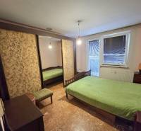A bedroom in a 3-room apartment with a large wardrobe, a bed, and green bedding on the bed.