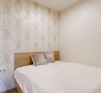 A cozy bedroom with a comfortable bed and patterned wallpaper in a studio apartment.