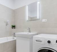 Bathroom with a bathtub, sink, and washing machine in a 3-room apartment, neutral colors.