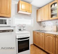 A kitchen in a cabin with wooden cabinets, a stovetop, and a microwave.