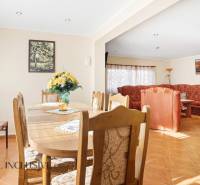 Interior of a cottage with a dining table, floral decoration, and a comfortable sofa.