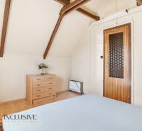 A room in a cottage with a chest of drawers, a chair, and a floor with a wooden decor.