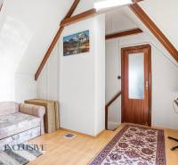 Attic room in a cottage with a chair, carpet, and table, wooden decor flooring.