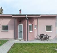 A family house in Šurany with a pink facade and a garden seating area on a paved walkway.