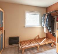 A room in a family house with shelves, a hanger, and simple furniture.