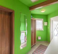 Entrance hall in a family house with green walls and a mirror.