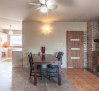 Dining room with a brick wall, fireplace, and kitchen in a family house.