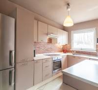 A kitchen in a family house with brick cladding and light furniture.