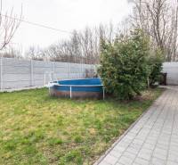 The garden of a family house in Šurany with a swimming pool, walkway, and trees.