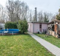 The garden of a family house in Šurany with a pool and a shelter, surrounded by greenery.