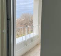 View from the room to the balcony of a 2-room apartment overlooking greenery.