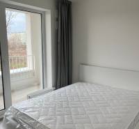 Bedroom with a bed and curtains in a 2-room apartment, floor with wooden decor.
