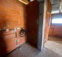 Interior of a family house under construction with raw brick walls and wiring.