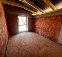 A room in a family house with unplastered brick walls and roof beams.