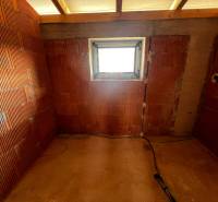 A room in a family house with raw brick walls and a window.