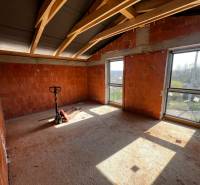 An unfinished room in a family house with raw brick walls and large windows.