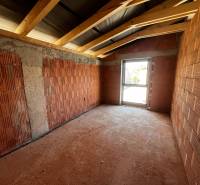 The interior of a family house in the construction phase with brick walls and ceiling beams.