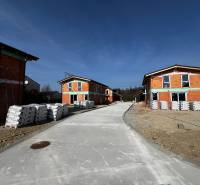 Family houses under construction on Lesná Street in Stupava, with piles of building materials.