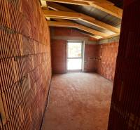 Construction of the interior of a family house with brick walls and a window in the background.