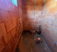 A room construction in a family house with a brick wall and bare floor.