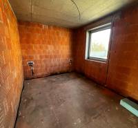 Unfinished interior with brick walls and unfinished concrete floor in a family house.
