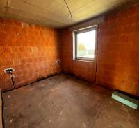 A room in a family house with raw brick walls and a window.