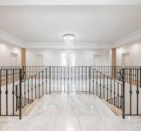 The interior of a family house with a dominant chandelier and metal railing.