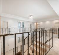 Interior of a family house with a staircase, railing, and chandelier.